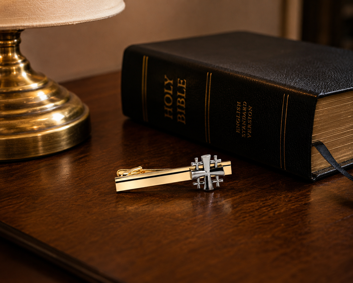 Holy Bible with a decorative key on a wooden surface next to a lamp.