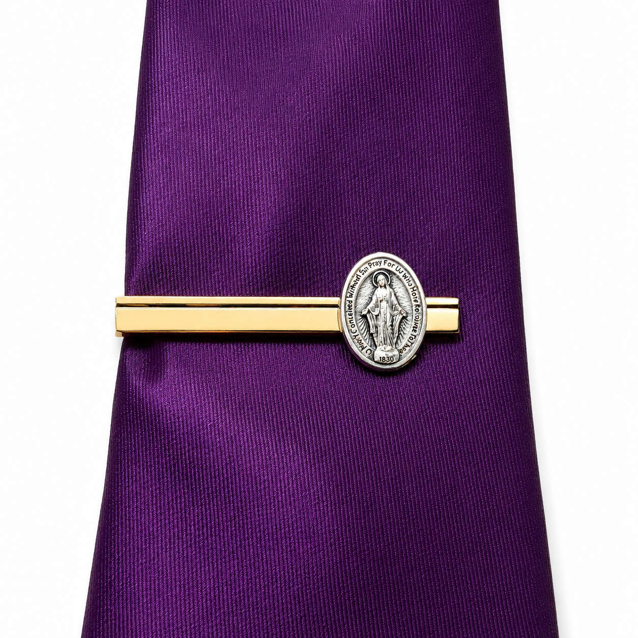 A purple necktie with a gold and silver Miraculous Medal tie clip, shown against a plain white background.