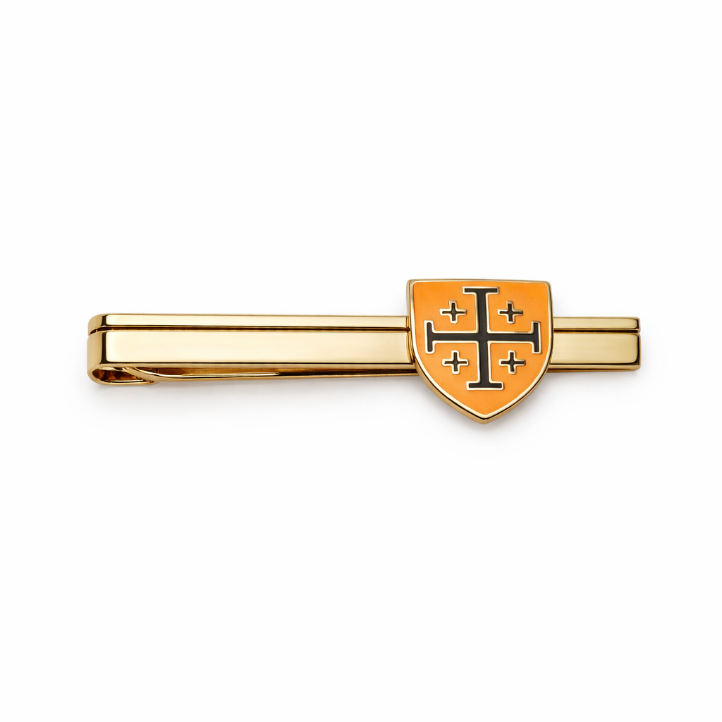 Gold tie clip with orange and black cross emblem on a white background