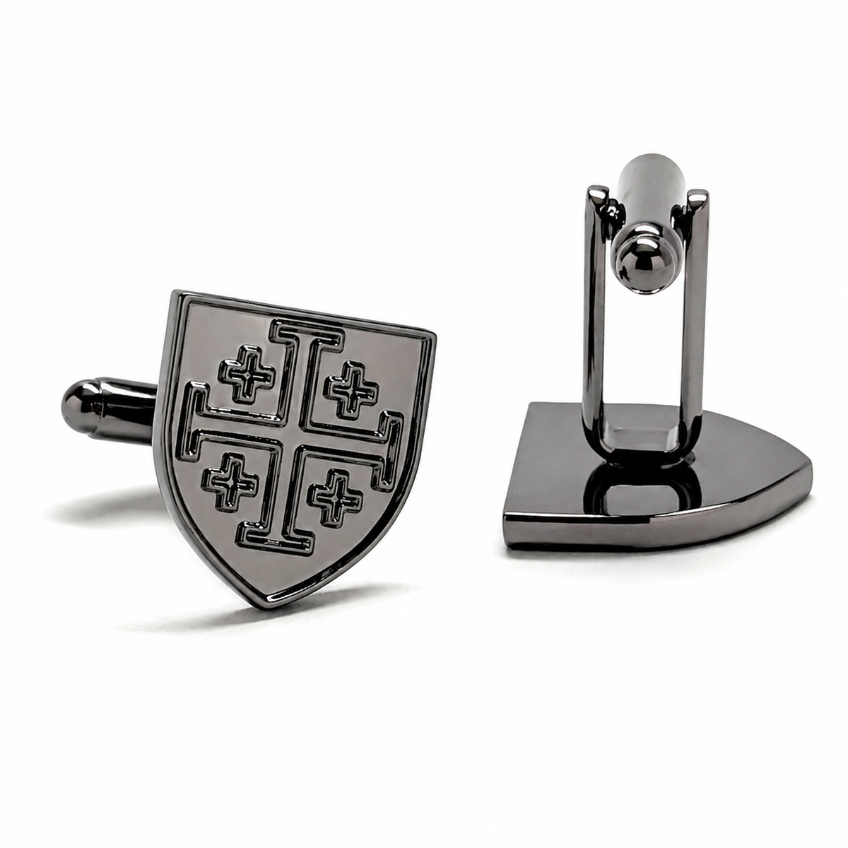 A pair of dark metallic cufflinks on a clean white background. One cufflink is shown from the front, featuring a shield-shaped face with a blackened cross motif on a silver-toned base.