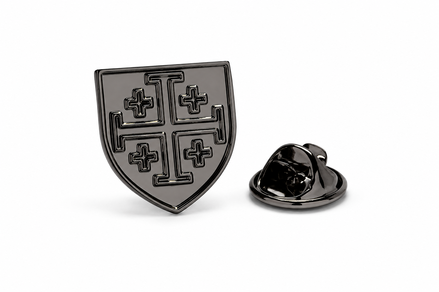 A black enamel shield-shaped lapel pin with a cross motif, shown alongside its silver-toned metal clutch backing on a clean white background.