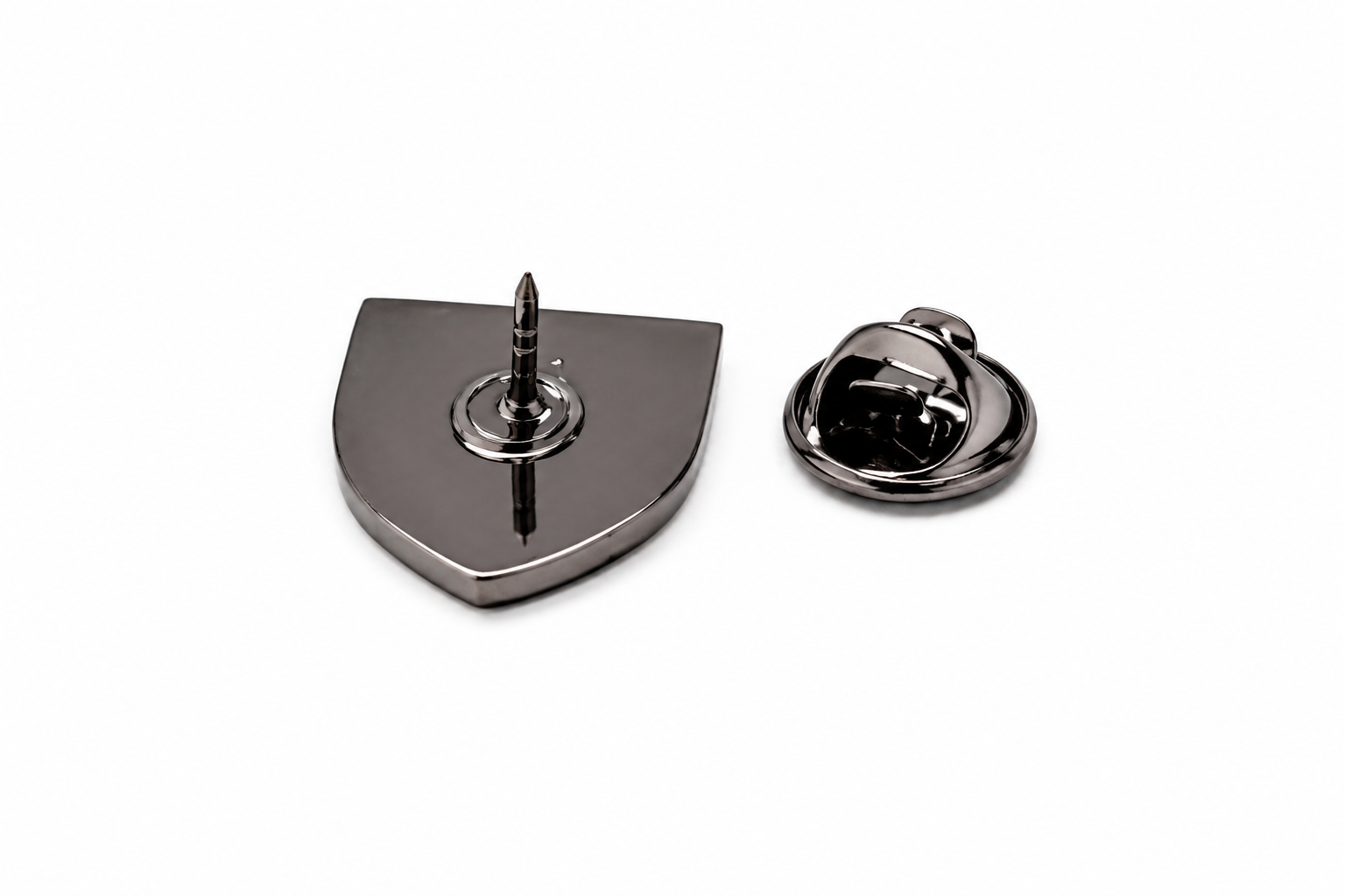 A metallic shield-shaped lapel pin shown from two angles on a plain white background: one view displays the front with a central pin, and the other shows the reverse clasp mechanism.