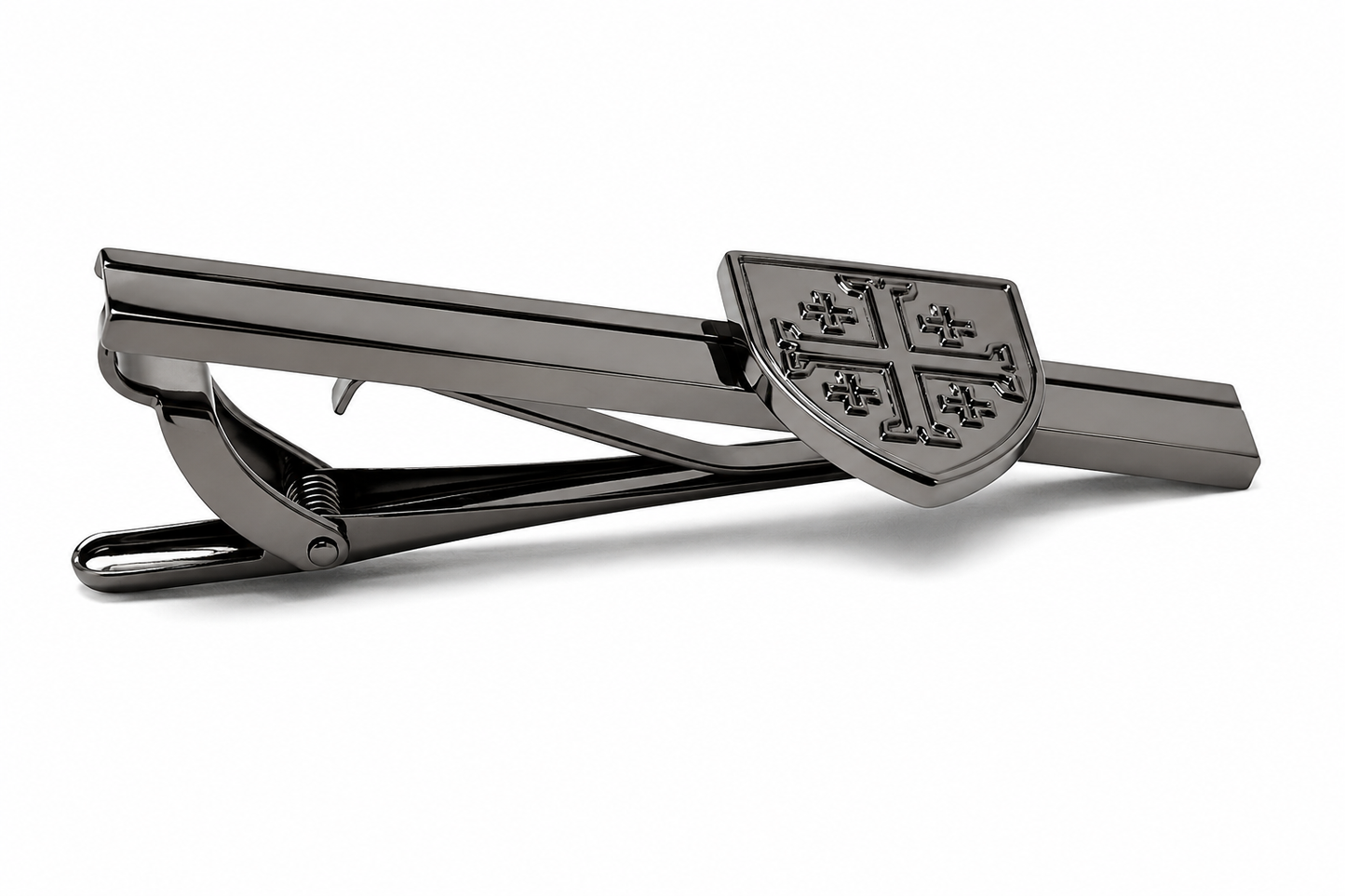 A dark metallic tie clip featuring a shield-shaped clasp with a raised cross motif, shown on a clean white background.