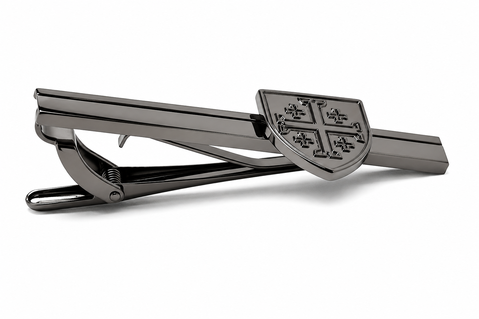 A dark metallic tie clip featuring a shield-shaped clasp with a raised cross motif, shown on a clean white background.