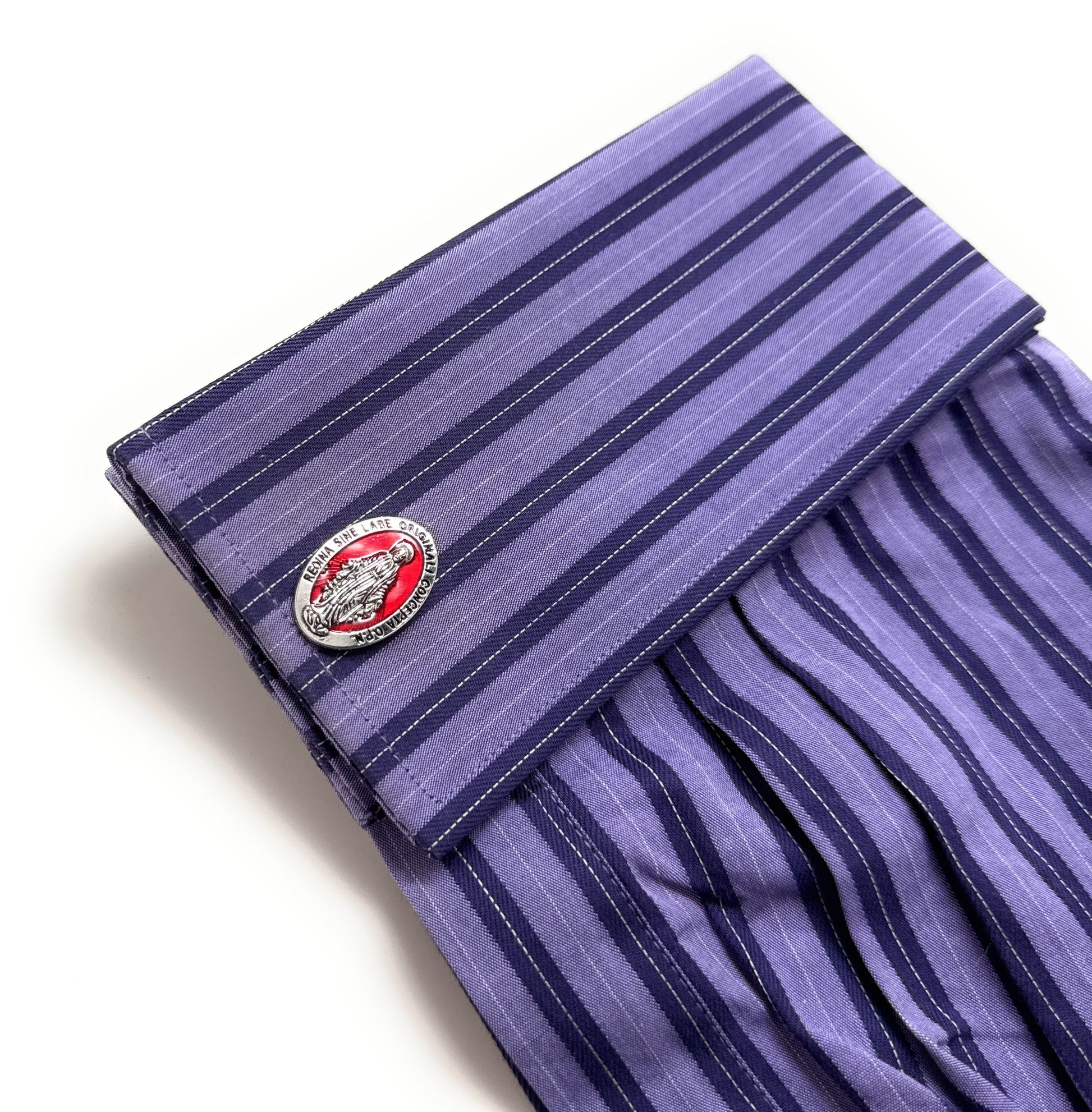 Folded purple striped shirt with a cufflink on a white background