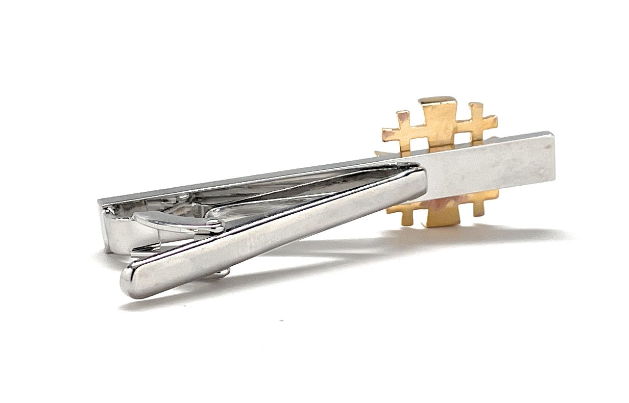 Silver and gold tie clips on a white background