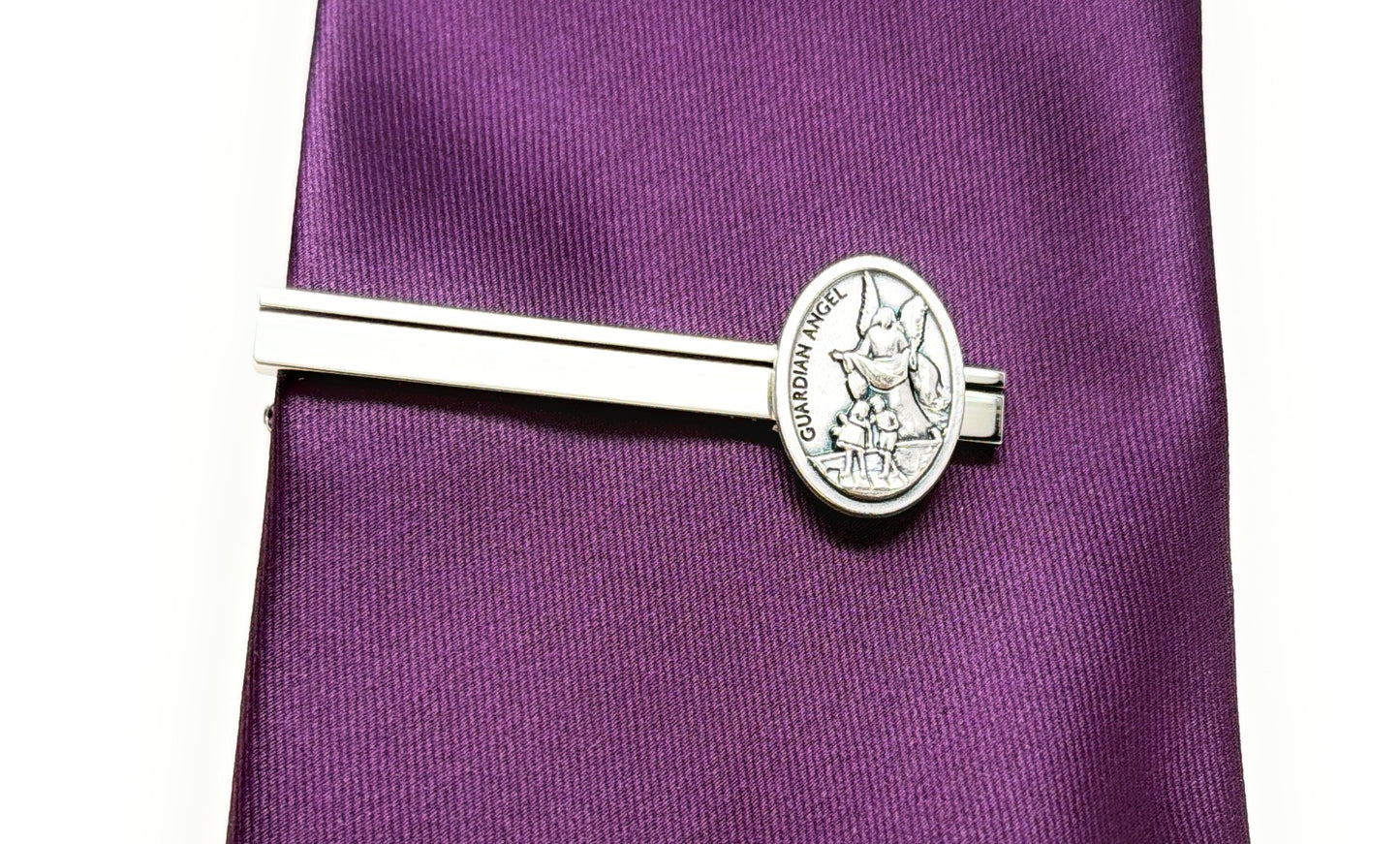 Silver tie clip on a purple tie with a white background