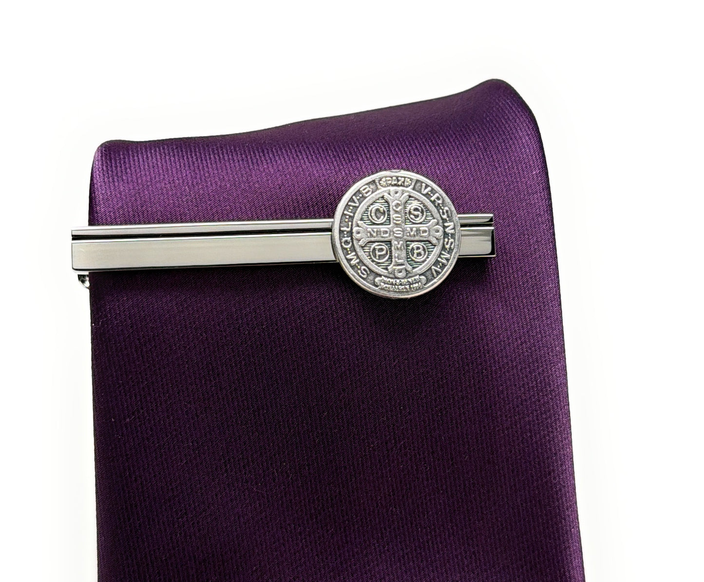 Silver tie clip on a purple tie against a white background