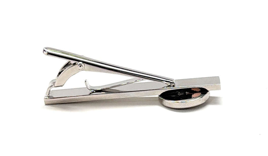 Silver tie clip with a small round component on a white background