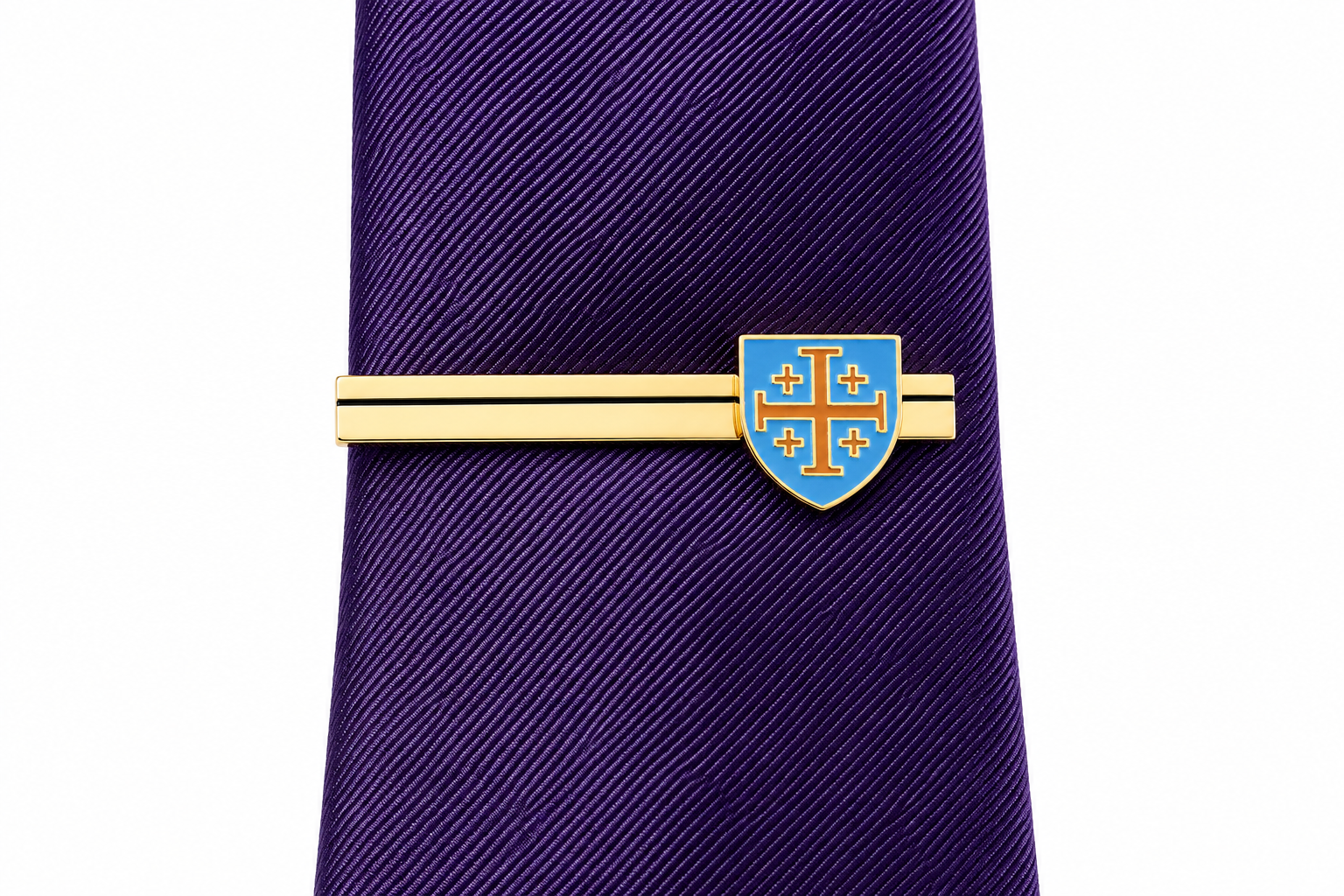 A purple textured necktie with a gold-toned tie clip featuring a blue and gold shield crest, shown against a plain white background.