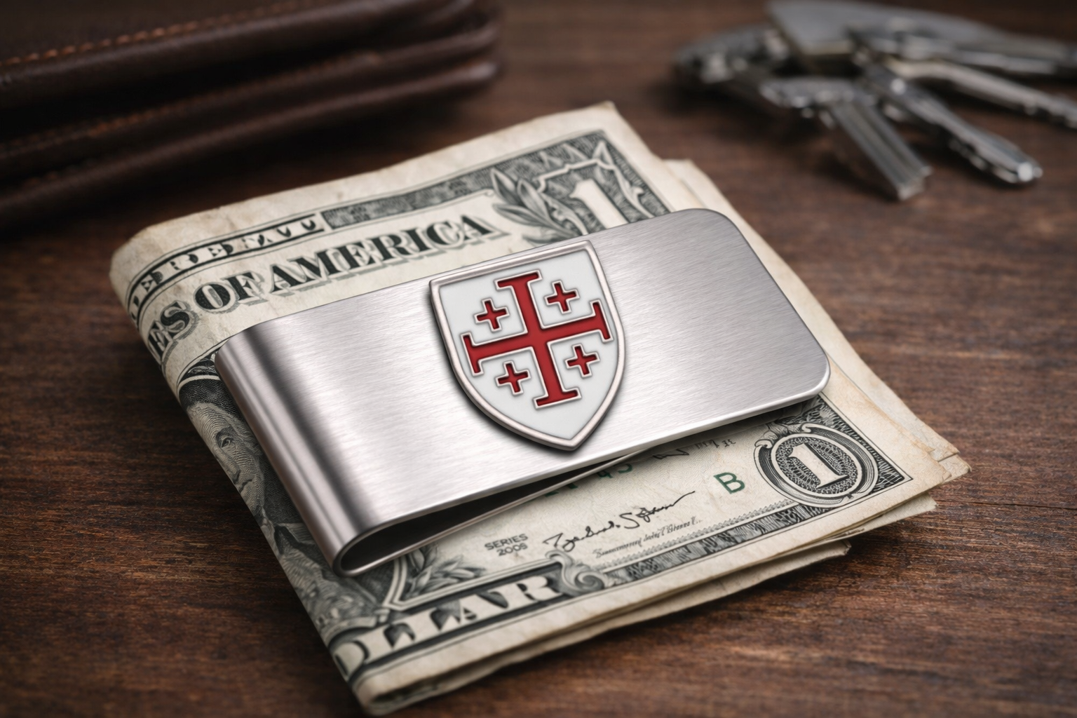 Silver money clip with a shield design Jerusalem Cross stainless steel money clip Christian religious accessory for men on top of U.S. dollar bills on a wooden surface.