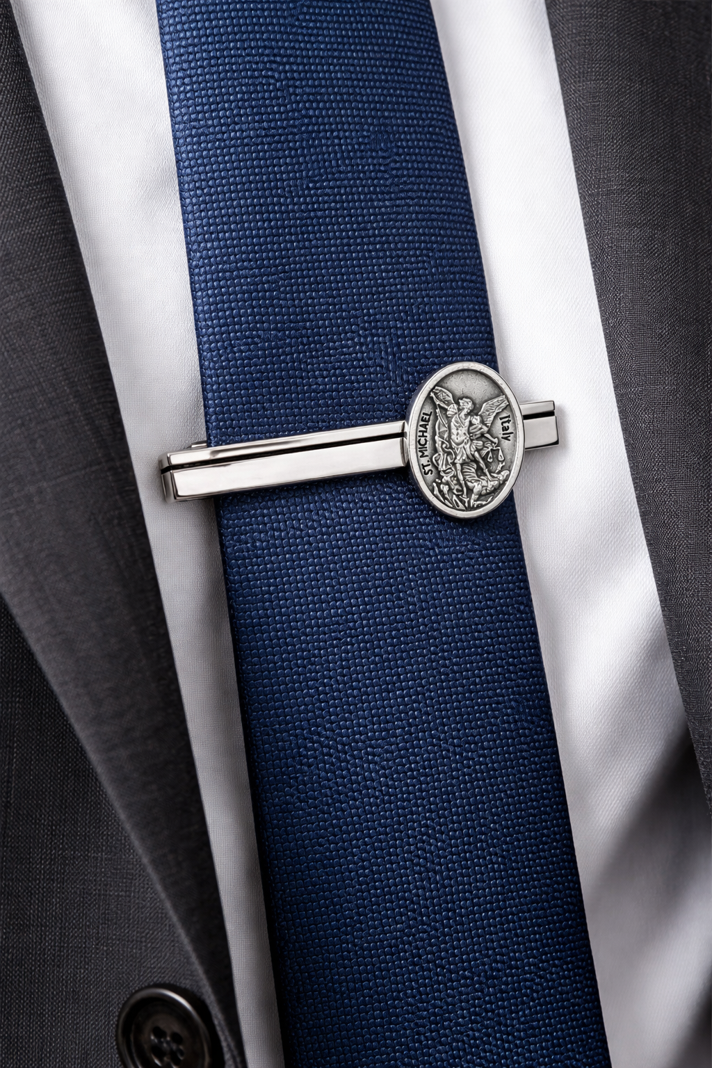 Navy blue tie with a silver tie clip St Michael on a gray suit and white shirt
