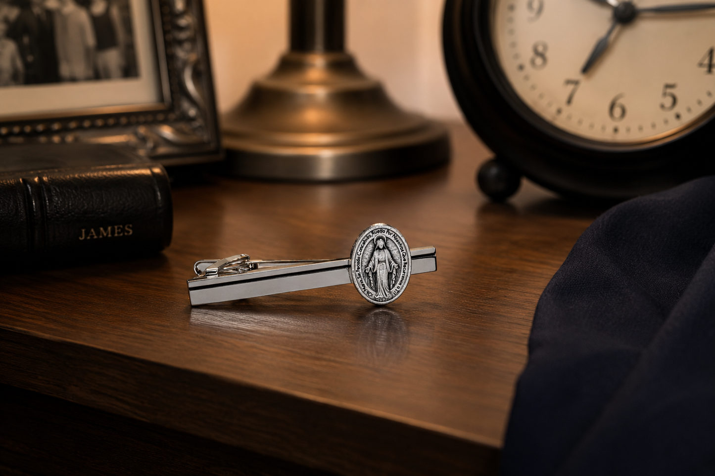 Silver tie clip on a wooden surface with a clock and photo frame in the background Spanish Mother of Mary tie Clip