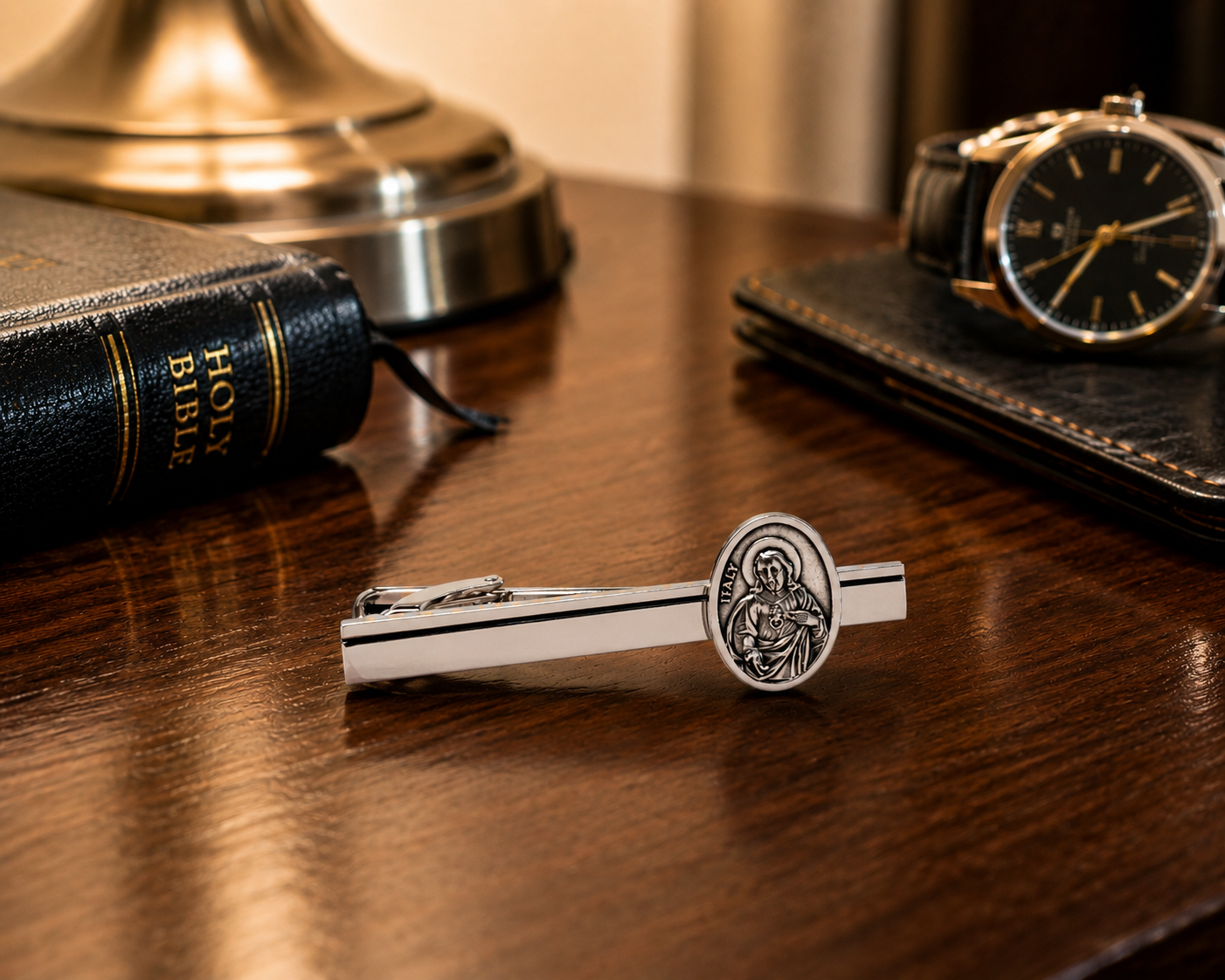 Silver Sacred Heart tie clip displayed beside Bible and formal accessories on nightstand