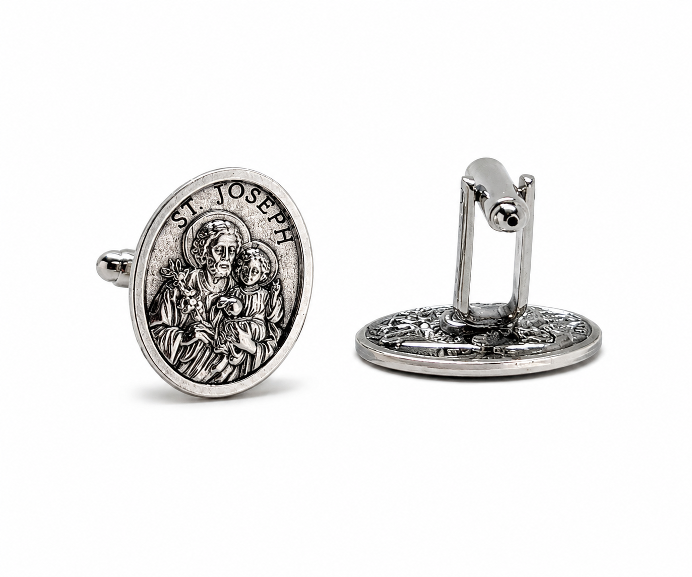 A pair of silver-toned cufflinks featuring an embossed religious medallion of St. Joseph and child, shown on a clean white background with one front-facing and one side-profile view.