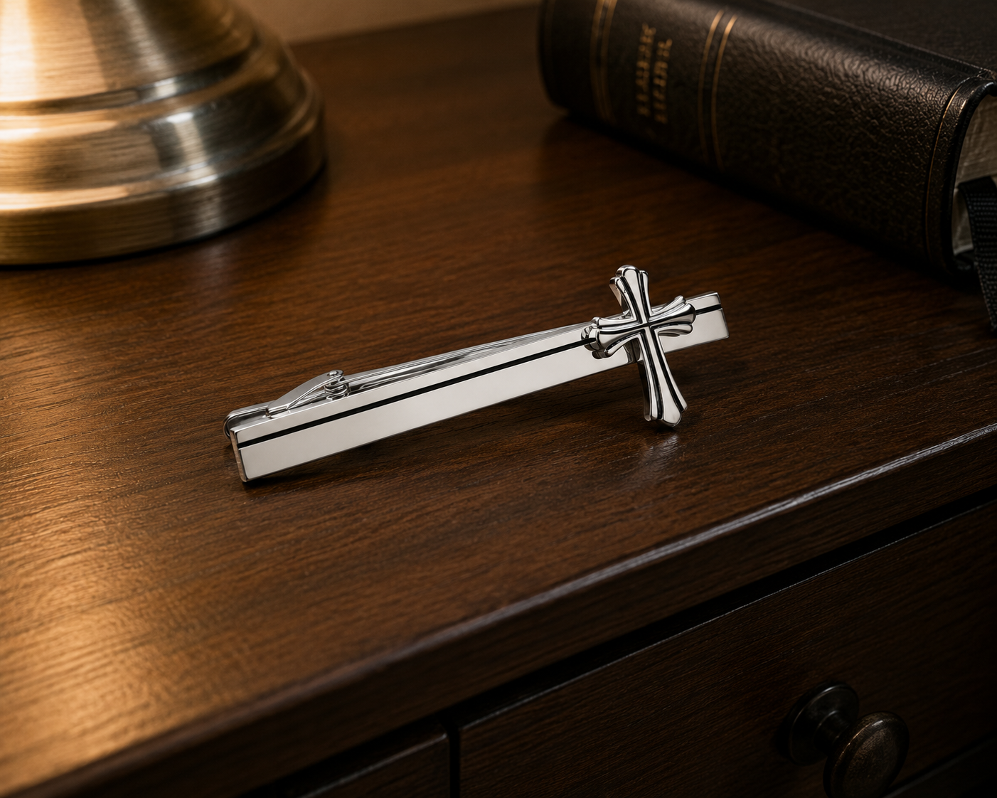 Silver tie clip with cross design on a wooden surface